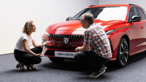 Auto Express editor Paul Barker crouching in front of the facelifted Peugeot 308