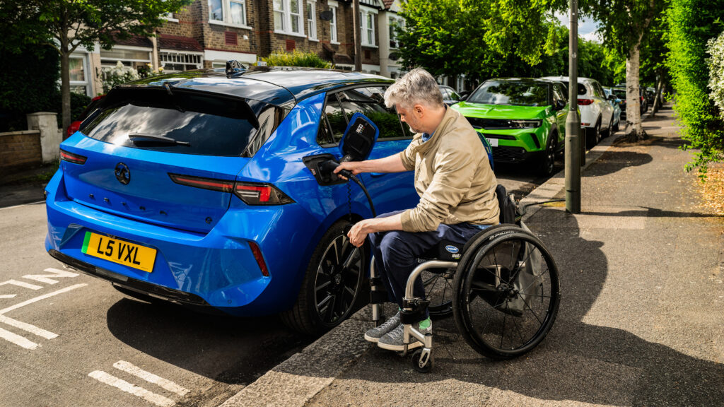 Wheelchair user plugging a charging cable into a Vauxhall Astra Electric